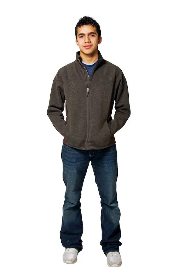 A young man stands with his hands in his hoodie pockets.