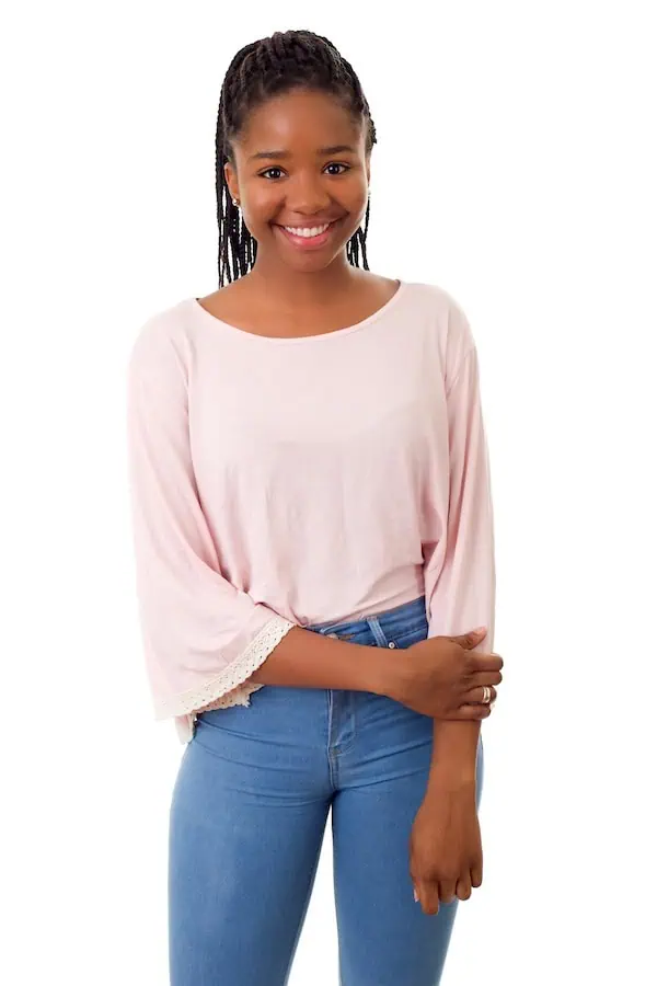 A young woman stands on a white backdrop smiling at the camera.